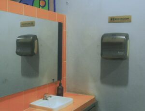 Hand dryer mounted on the wall of a public restroom next to sink and mirror